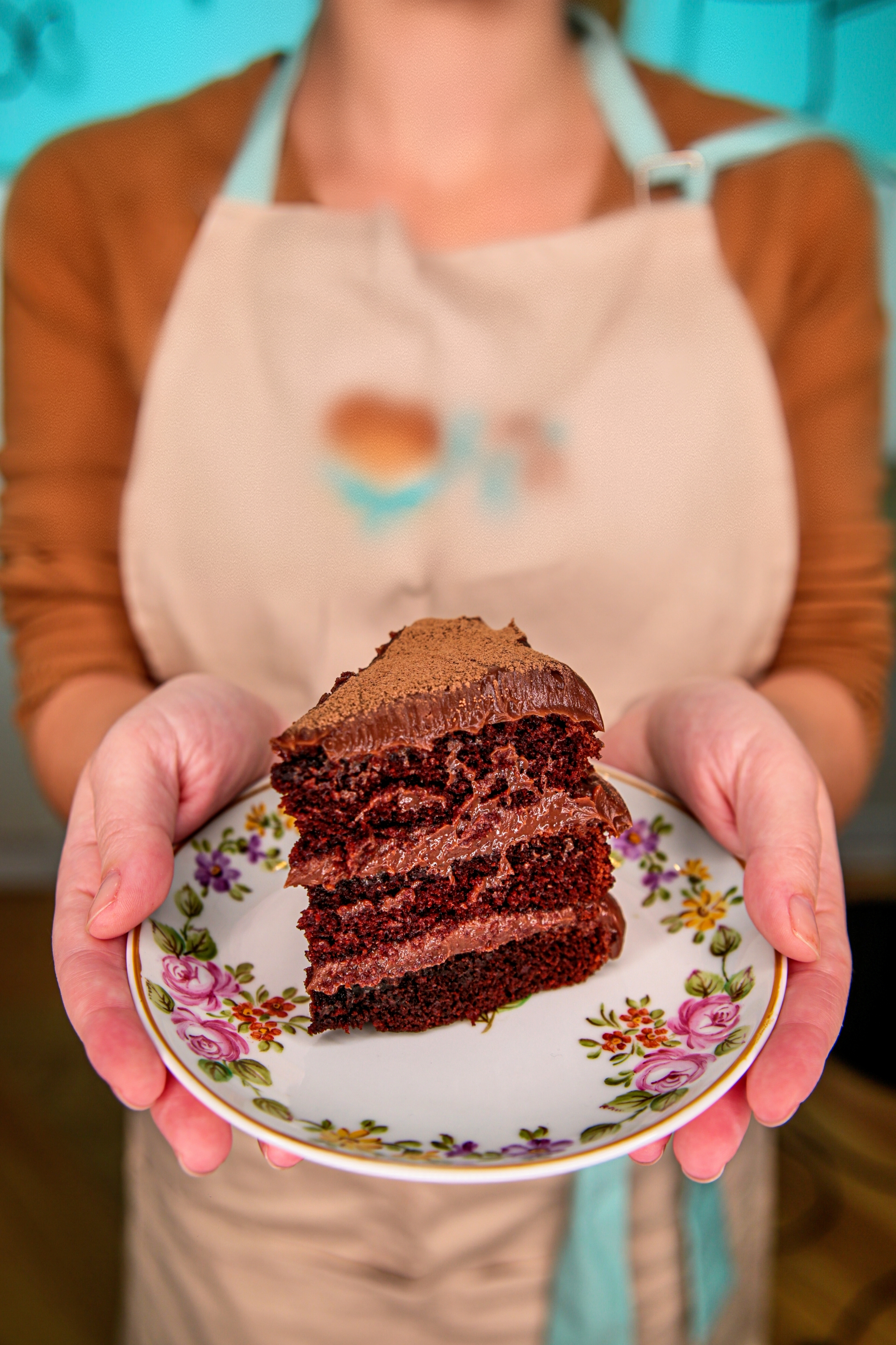 Fatia de bolo artesanal de chocolate da confeitaria As Veras, servida em prato floral, com camadas úmidas e recheio cremoso.