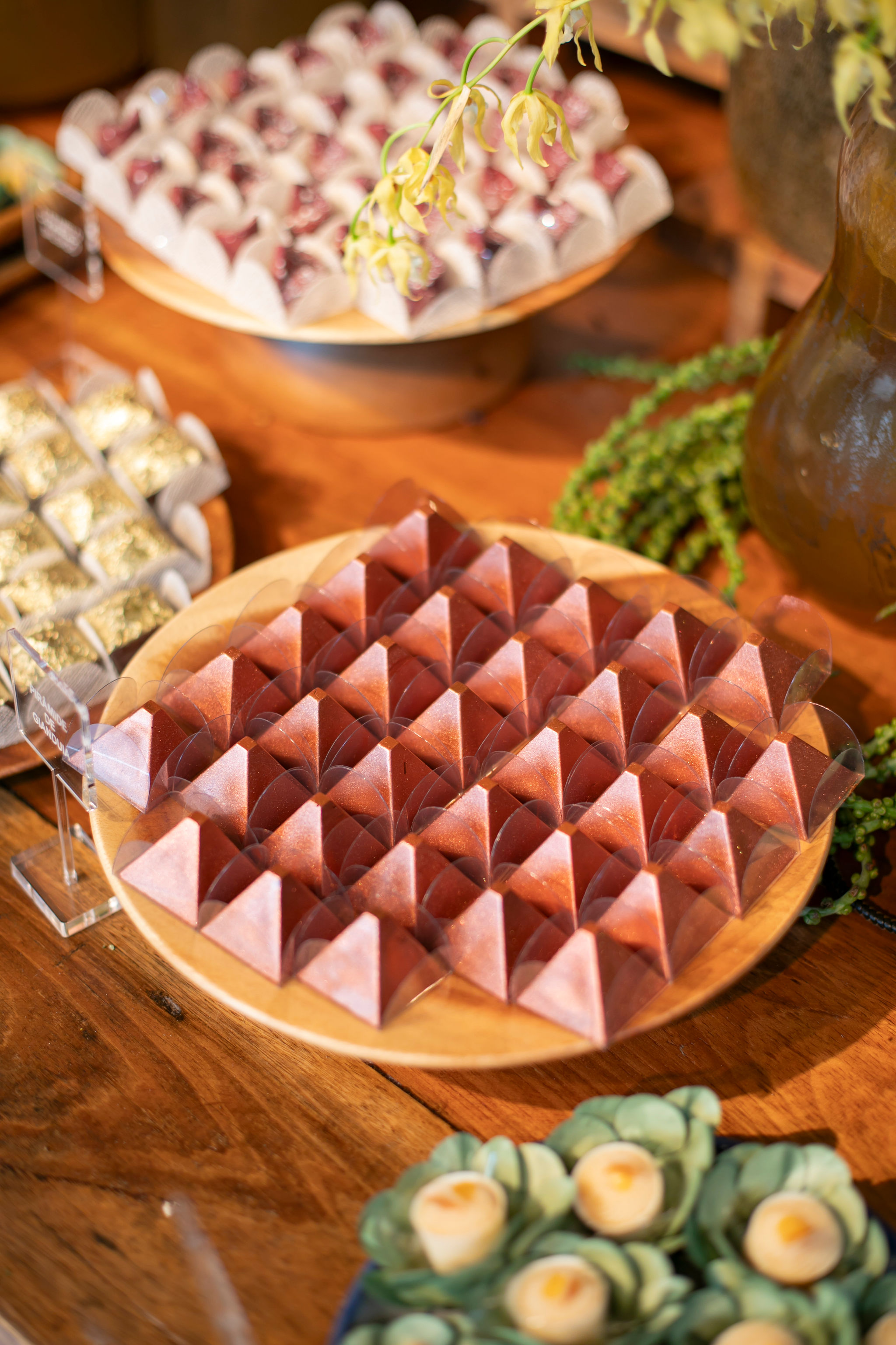 Mesa de doces para casamento com doces finos em formato de pirâmide, dispostos em bandeja de madeira, compondo uma apresentação elegante e sofisticada.